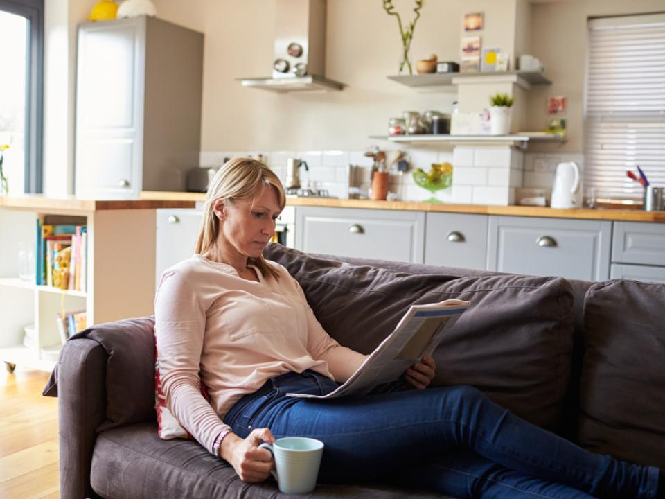 Woman reading newspaper on sofa